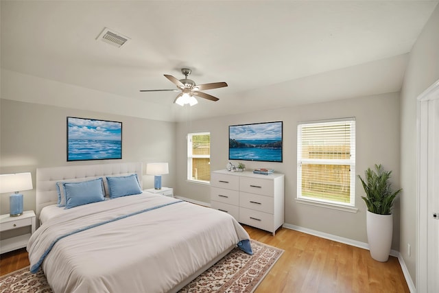 bedroom with light wood-style flooring, visible vents, a ceiling fan, and baseboards