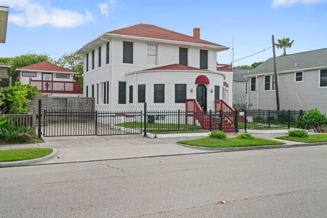 traditional style home with stucco siding, a chimney, and a fenced front yard