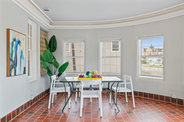 dining room with baseboards, ornamental molding, visible vents, and plenty of natural light