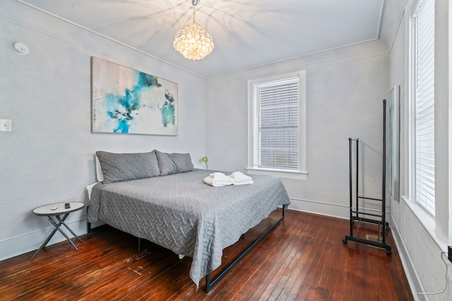 bedroom featuring baseboards, crown molding, hardwood / wood-style flooring, and a notable chandelier