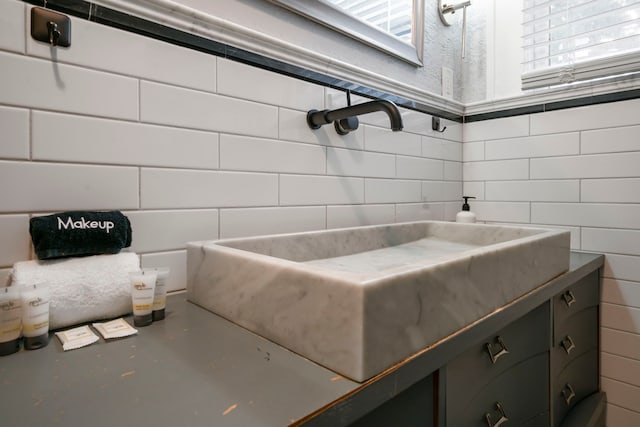 bathroom with tile walls, finished concrete floors, decorative backsplash, and a sink