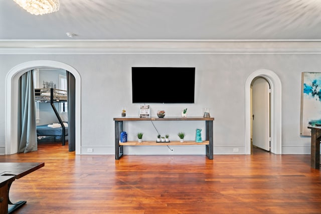 living room with baseboards, wood finished floors, arched walkways, and ornamental molding