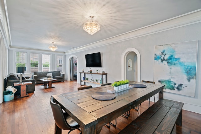 dining area with arched walkways, baseboards, a chandelier, wood finished floors, and crown molding