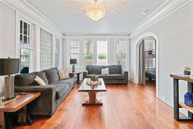 living area featuring wood finished floors, arched walkways, a chandelier, and ornamental molding