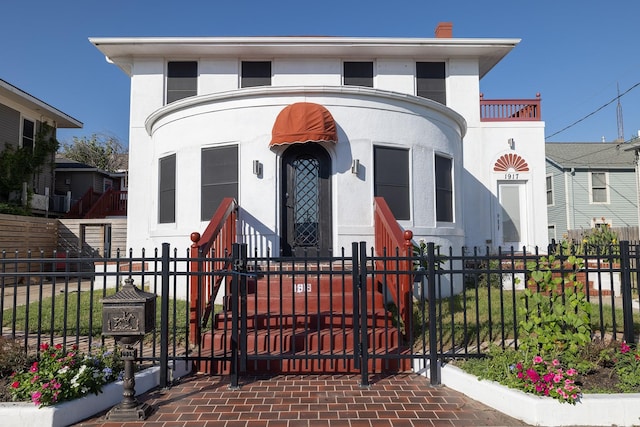 view of front facade with stucco siding and a fenced front yard