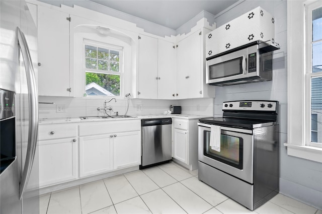 1919 Rosenberg St, Galveston, TX 77550 - kitchen with appliances with stainless steel finishes, a sink, white cabinets, and decorative backsplash