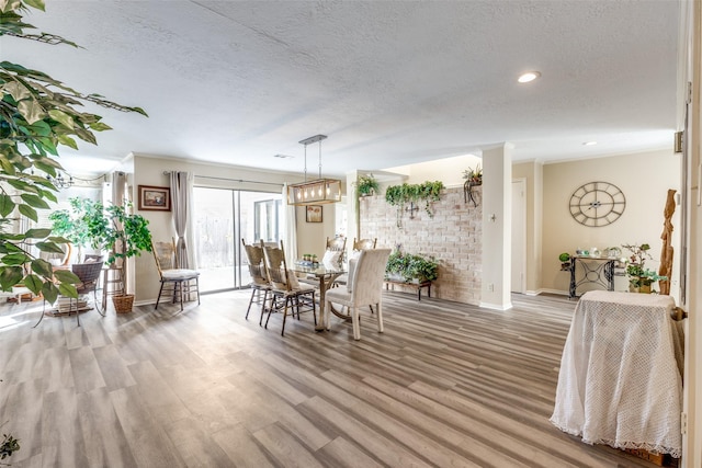 dining area featuring a textured ceiling, light wood finished floors, and baseboards