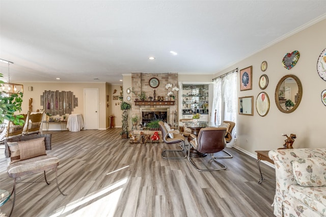 living room featuring recessed lighting, wood finished floors, ornamental molding, baseboards, and a fireplace
