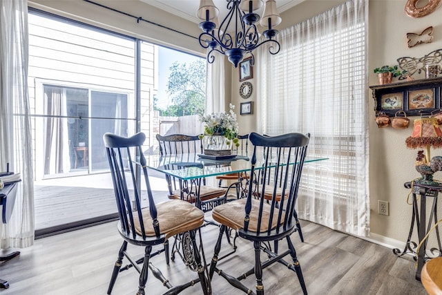 dining room featuring wood finished floors, a chandelier, a textured wall, baseboards, and ornamental molding