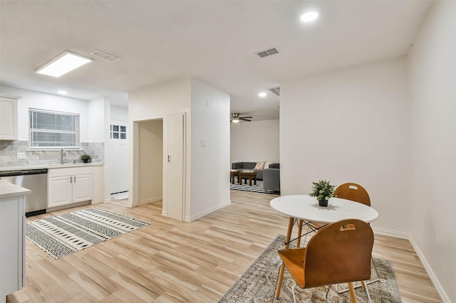 105 E Wavy Oak Cir, The Woodlands, TX 77381 - kitchen featuring stainless steel dishwasher, light wood-style flooring, backsplash, white cabinets, and light countertops