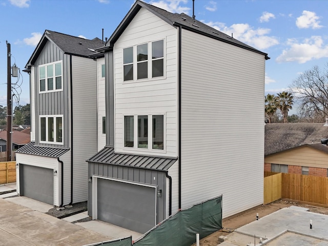 exterior space featuring a standing seam roof, metal roof, fence, an attached garage, and board and batten siding