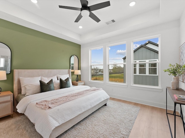 bedroom featuring ceiling fan, a tray ceiling, light wood-style flooring, visible vents, and recessed lighting