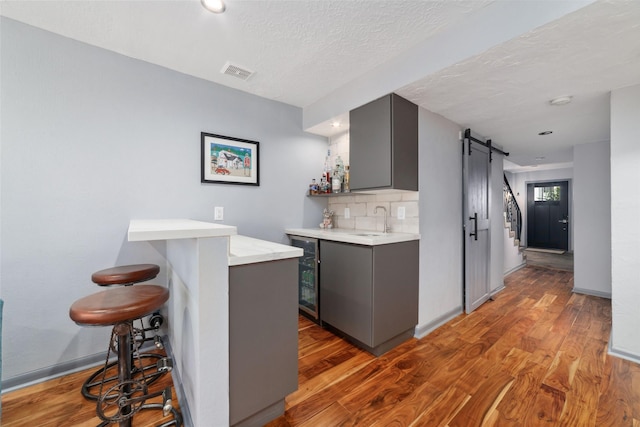 8924 Chatsworth Dr, Houston, TX 77024 - kitchen with a barn door, gray cabinets, wine cooler, light countertops, and wood finished floors
