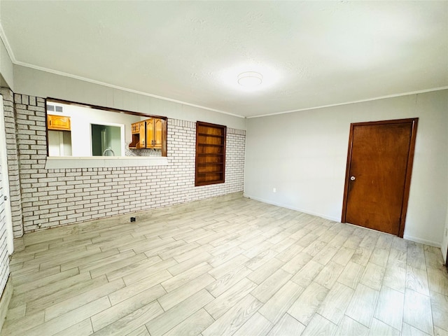 7905 Turquoise Ln, Houston, TX 77055 - empty room featuring light wood finished floors, brick wall, crown molding, baseboards, and a textured ceiling