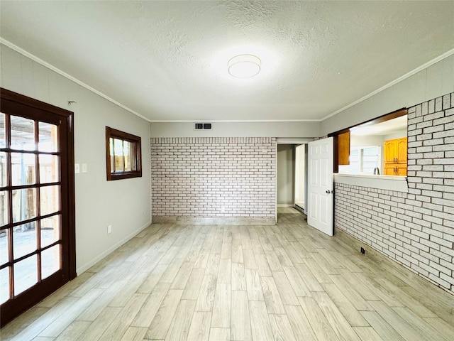 7905 Turquoise Ln, Houston, TX 77055 - spare room with brick wall, light wood-style floors, crown molding, a textured ceiling, and baseboards