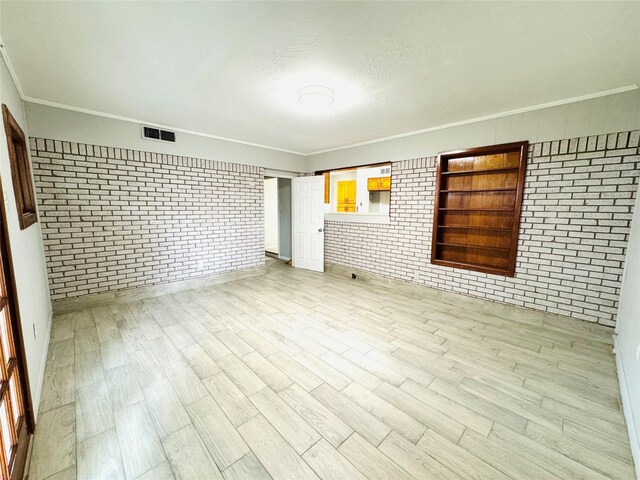 7905 Turquoise Ln, Houston, TX 77055 - unfurnished room with brick wall, light wood-style flooring, baseboards, ornamental molding, and a textured ceiling