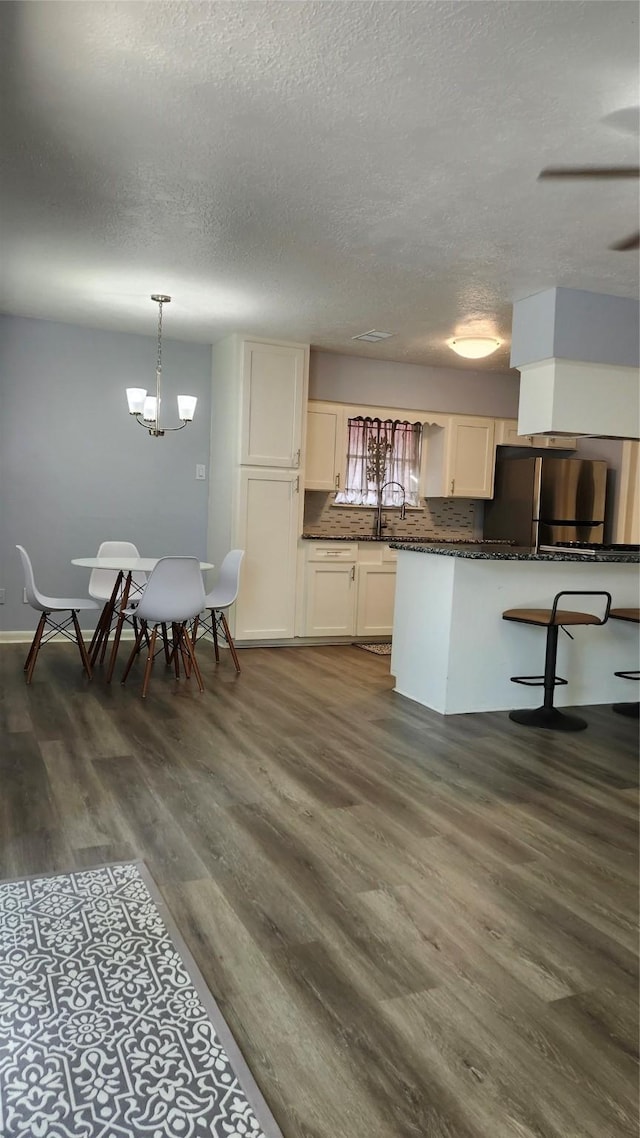kitchen featuring dark wood-style floors, a textured ceiling, an inviting chandelier, and freestanding refrigerator