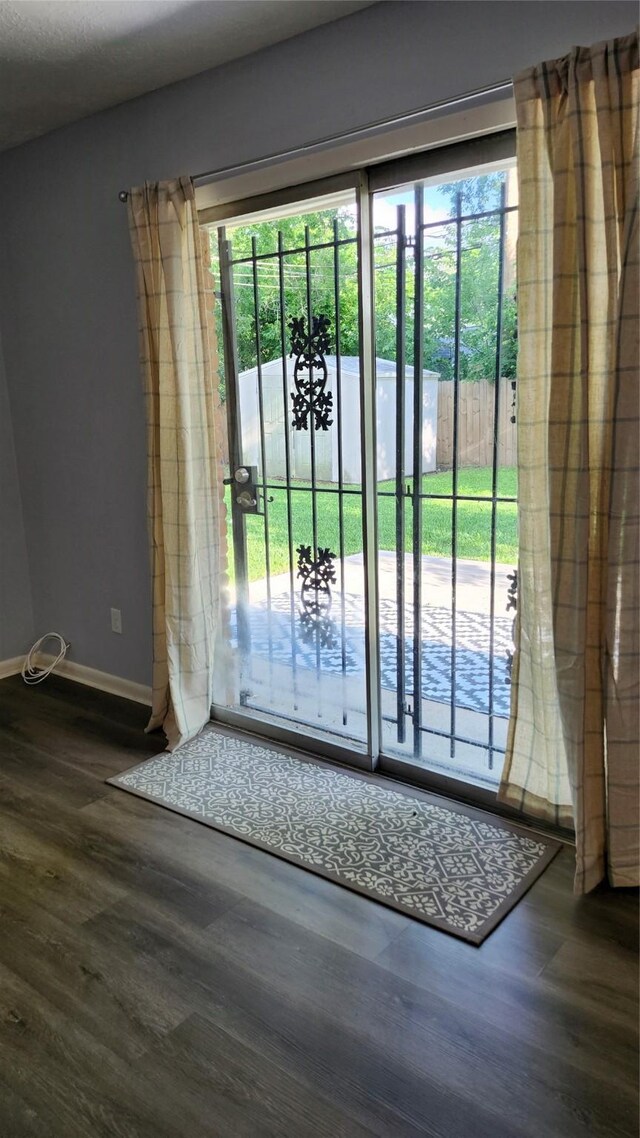doorway to outside featuring dark wood-style flooring and baseboards