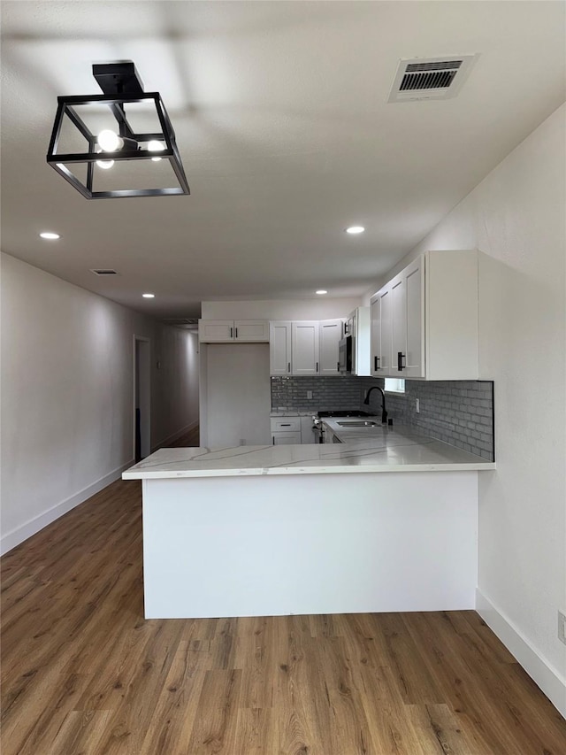 4414 Orange St, Houston, TX 77020 - kitchen with visible vents, a peninsula, baseboards, a sink, and backsplash