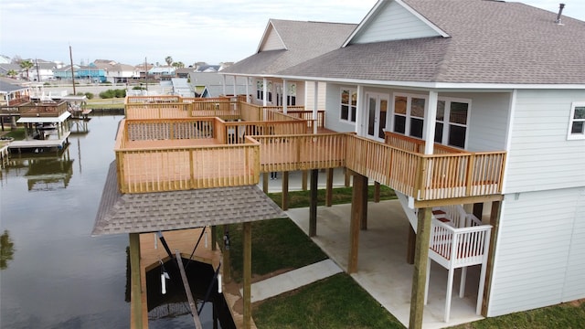 back of house featuring a shingled roof, a residential view, a water view, a patio, and a carport
