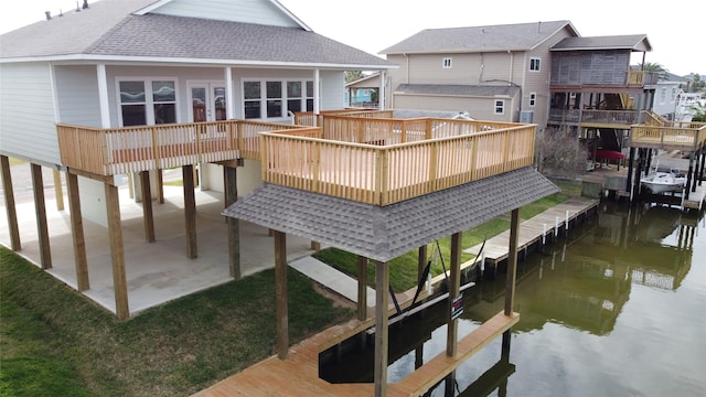 rear view of property with a deck with water view, french doors, and a shingled roof