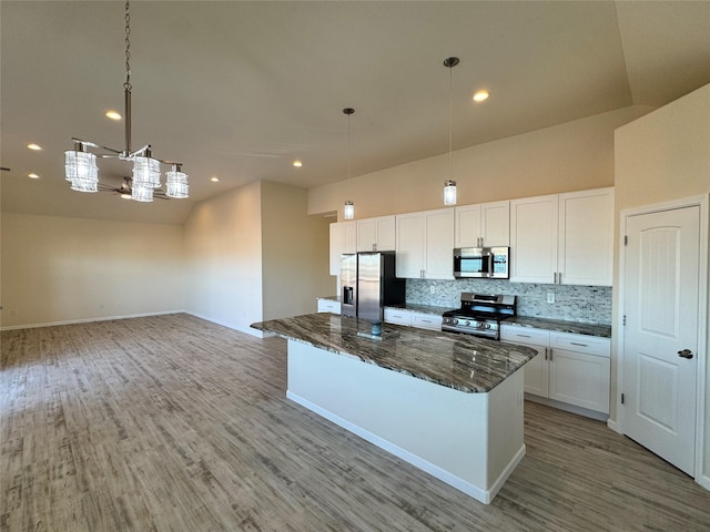 kitchen featuring dark stone countertops, light wood finished floors, white cabinets, backsplash, and appliances with stainless steel finishes