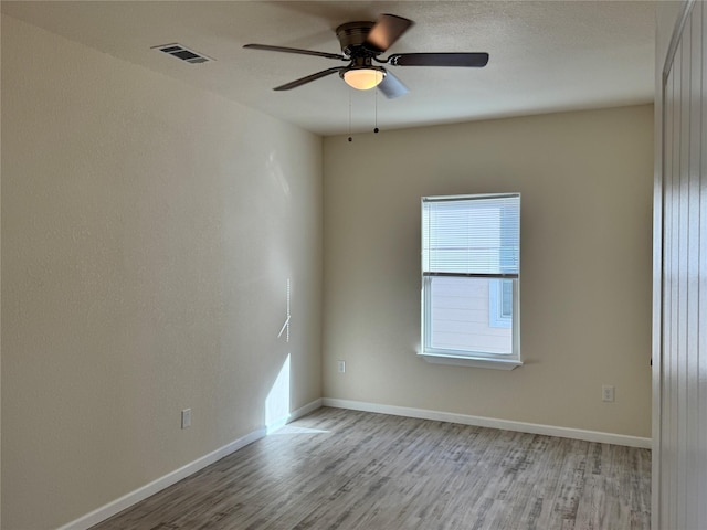 empty room with light wood-type flooring, visible vents, baseboards, and ceiling fan