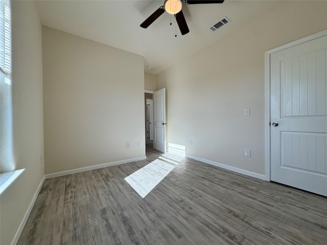 unfurnished bedroom with wood finished floors, visible vents, a ceiling fan, and baseboards