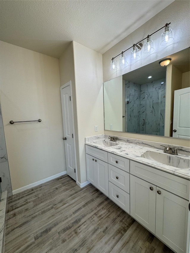 full bath with wood finished floors, a marble finish shower, and a sink