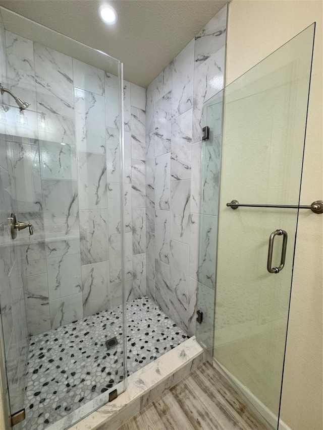 full bathroom with wood finished floors, a marble finish shower, and recessed lighting