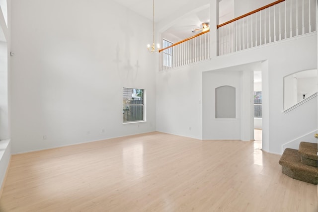 8010 Fox St, Baytown, TX 77523 - unfurnished living room with a towering ceiling, wood finished floors, baseboards, stairs, and ceiling fan with notable chandelier