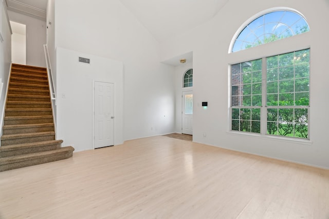 8010 Fox St, Baytown, TX 77523 - unfurnished living room featuring wood finished floors, visible vents, a towering ceiling, and stairway