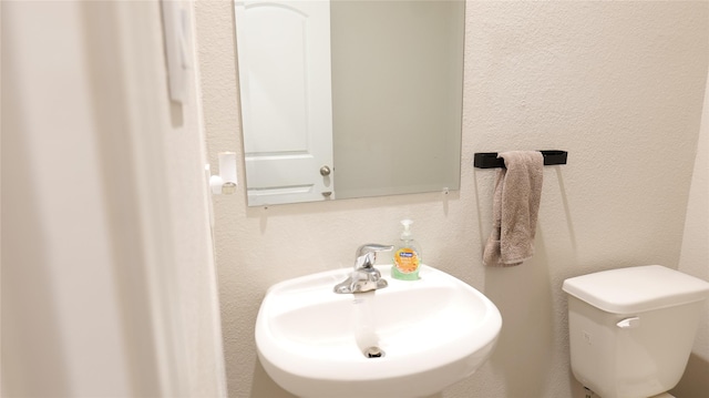 40607 Creekside Bluff Trl, Magnolia, TX 77354 - half bathroom with a sink, toilet, and a textured wall