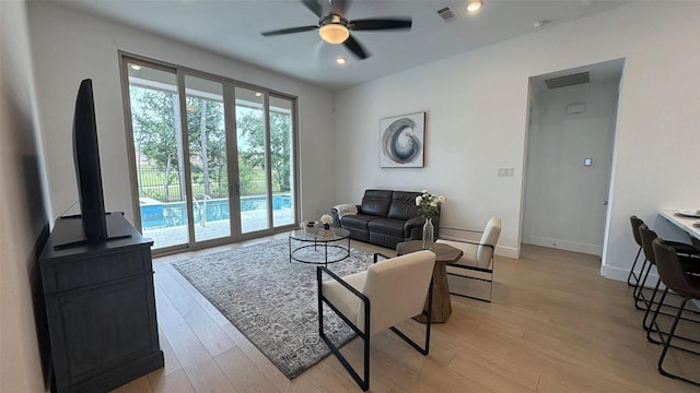 living room featuring ceiling fan, light wood-type flooring, and visible vents
