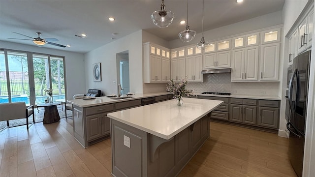 kitchen with light wood-style floors, ceiling fan, smart refrigerator, a center island, and a sink