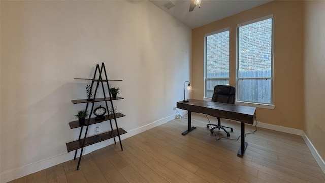 office space featuring light wood-style floors, baseboards, ceiling fan, and visible vents