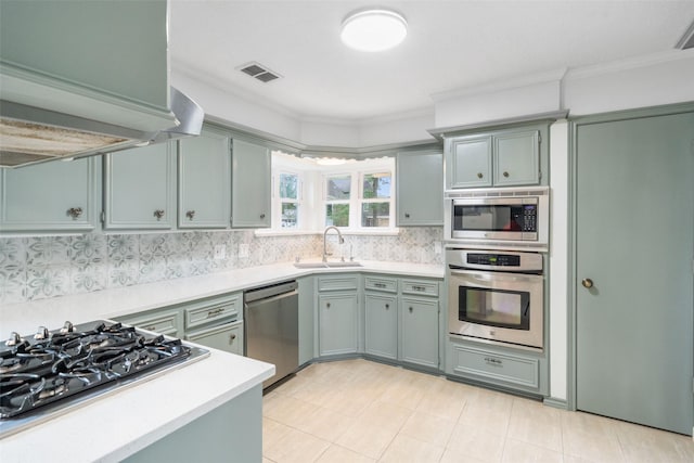 kitchen with appliances with stainless steel finishes, a sink, light countertops, decorative backsplash, and visible vents
