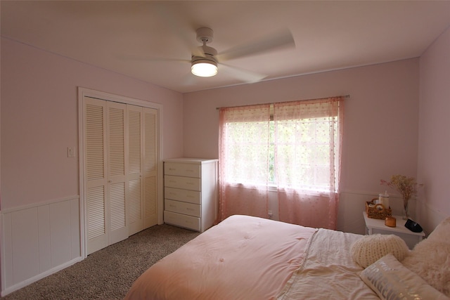 carpeted bedroom with a closet, a ceiling fan, and wainscoting