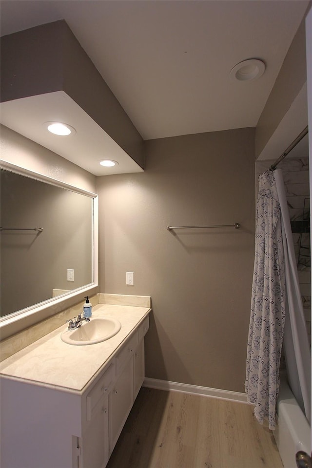 full bath featuring baseboards, wood finished floors, and vanity