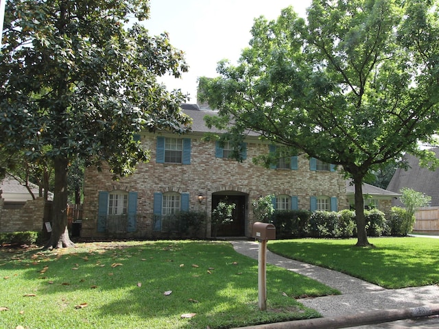 colonial inspired home featuring brick siding and a front yard
