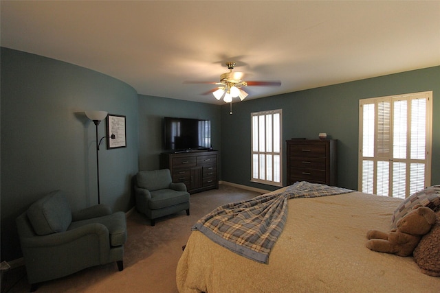 carpeted bedroom featuring a ceiling fan, baseboards, and multiple windows