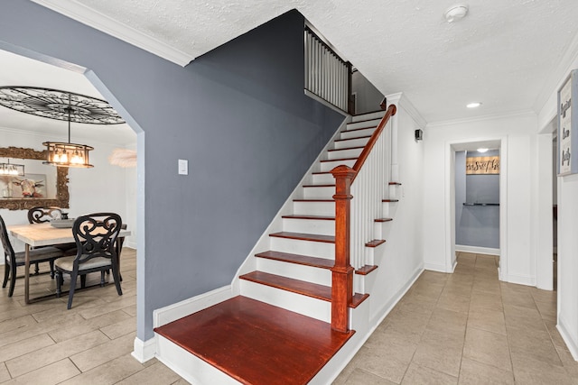 stairs with baseboards, ornamental molding, a textured ceiling, and an inviting chandelier