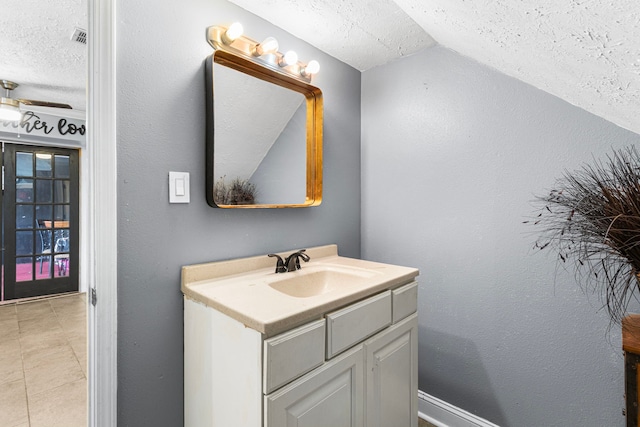 bathroom featuring tile patterned floors, vaulted ceiling, visible vents, vanity, and a textured ceiling