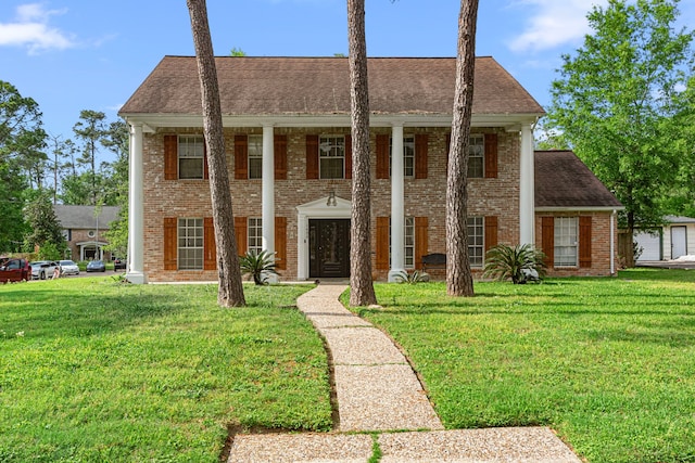 greek revival inspired property with a shingled roof, a front lawn, and brick siding
