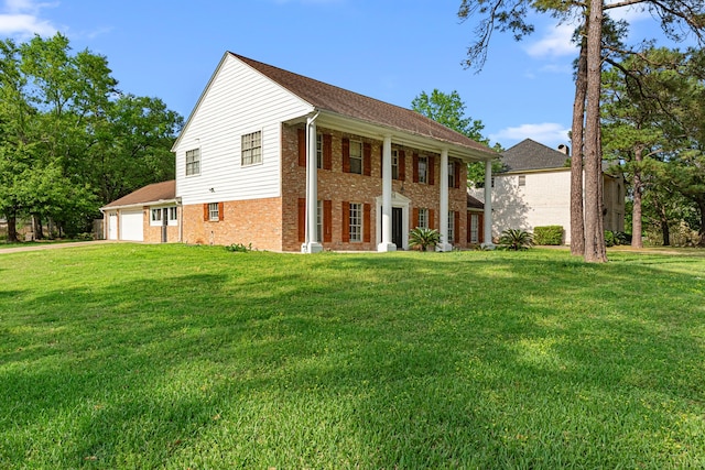 neoclassical / greek revival house with an attached garage, driveway, a front lawn, and brick siding