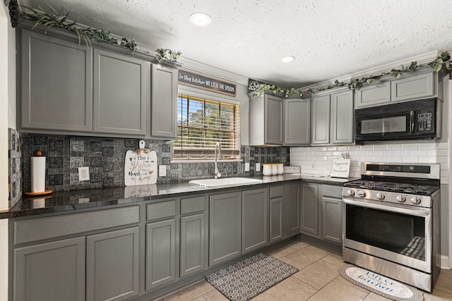 kitchen with black microwave, gas range, gray cabinetry, and a sink
