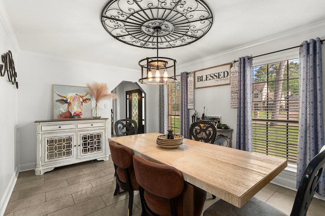 dining room featuring a chandelier, arched walkways, baseboards, ornamental molding, and dark tile patterned floors