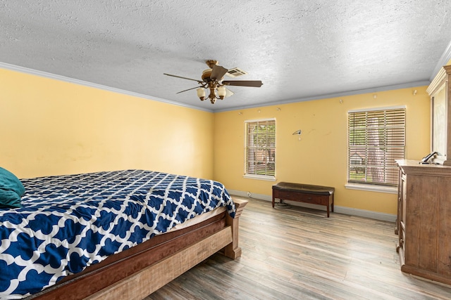 bedroom featuring crown molding, light wood-style floors, and a textured ceiling
