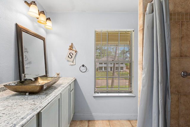 full bathroom with baseboards, vanity, tile patterned floors, and tiled shower