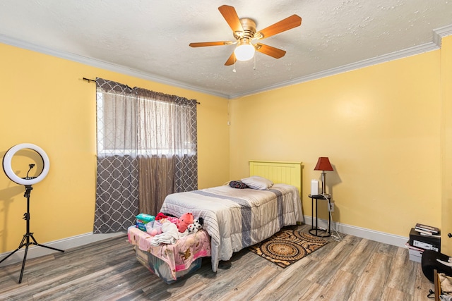 bedroom featuring wood finished floors, crown molding, and baseboards